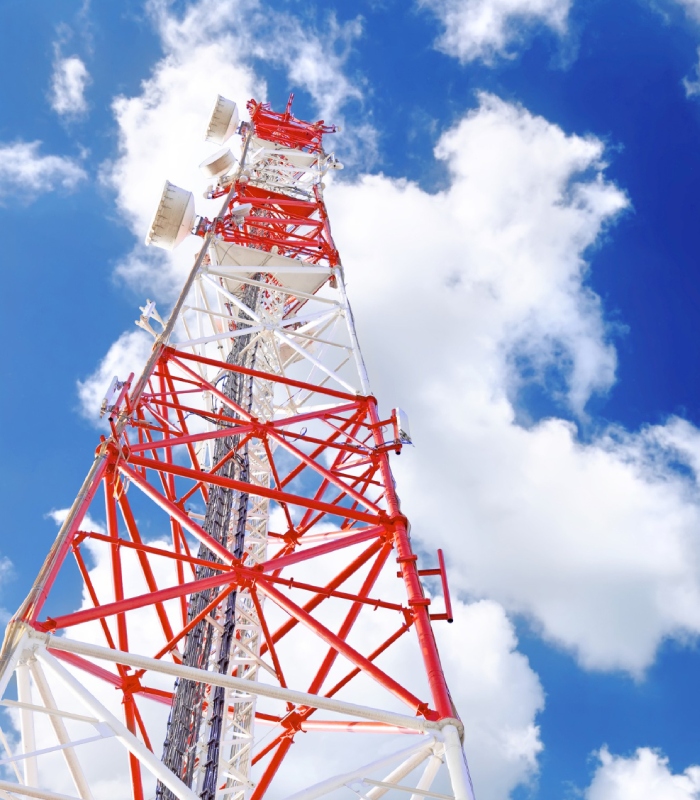 Pylône télécom rouge et blanc équipé d’antennes de communication sous un ciel bleu