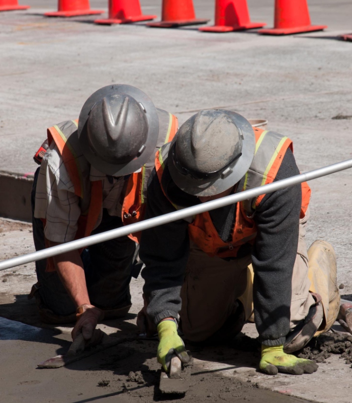 Deux ouvriers lissant un béton frais lors de la création d’un chemin d’accès en chantier