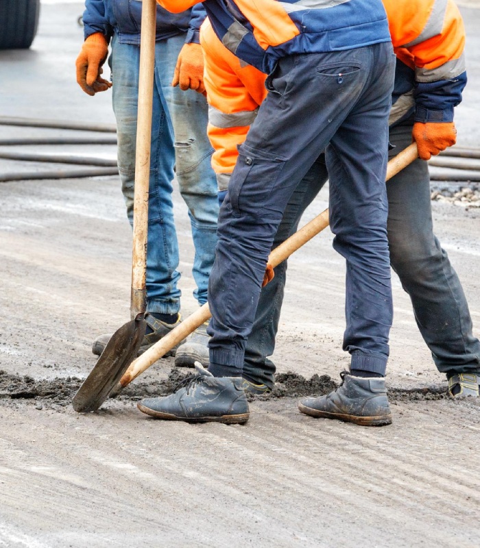 Ouvriers en tenue de chantier réalisant des travaux de voirie et d’accès avec pelle sur chaussée
